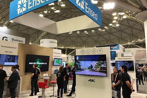 the Enseo booth at HITEC Minneapolis 2019. Several HD and 4K tvs on pillars with displays and many people observing/discussing the technology