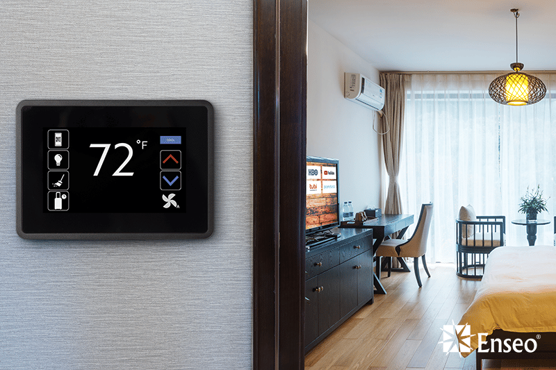 Modern hotel room featuring a digital thermostat set at 72°F, a neat bed, a television displaying content, a dining area, and ambient lighting.