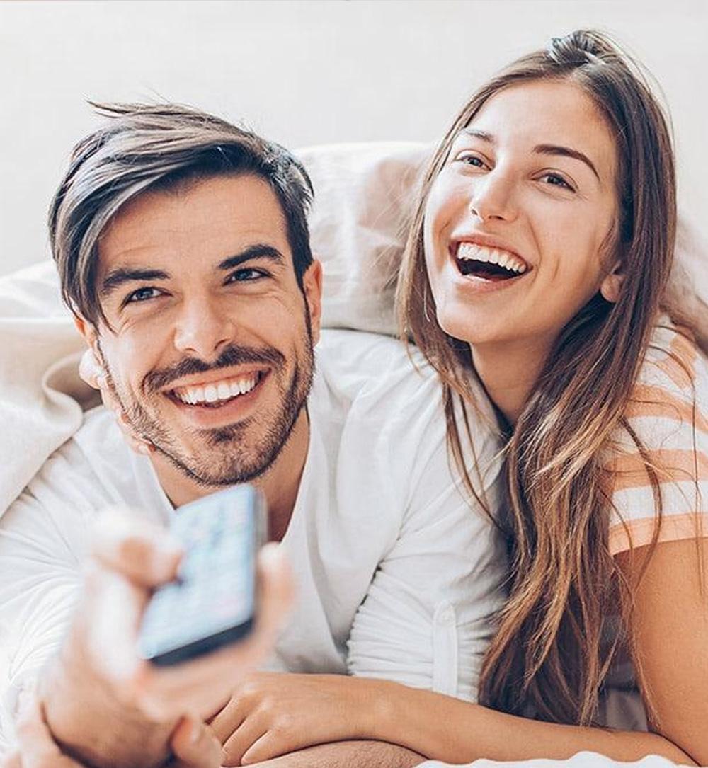 happy couple watching tv holding a remote control